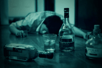 Пьяный мужчина лежит на полу среди бутылок